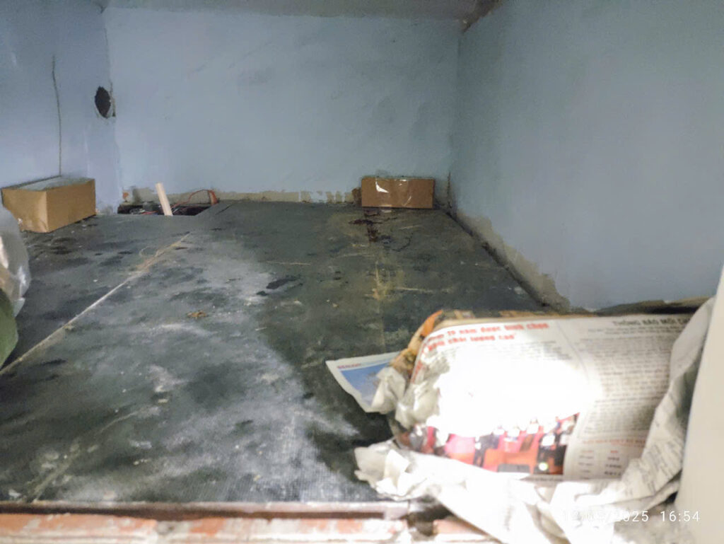 Tầng trệt đang sửa chữa với màng lót sàn bị mối cắn rách và tường có vệt ố